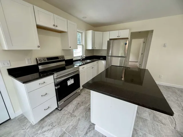 a kitchen with white cabinets and black appliances