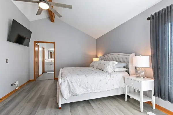 a bedroom with a bed wooden floor and flat screen tv