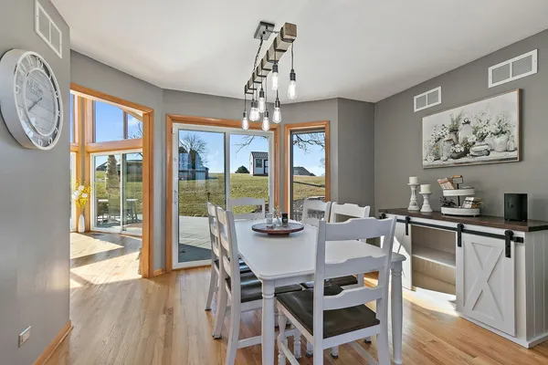 a view of a dining room with furniture large windows a chandelier and wooden floor