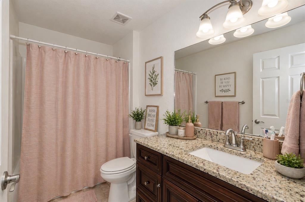 7153 Southeast 124th Street Belleview, FL 34420 - Photo 11 of 16 a bathroom with a granite countertop sink a toilet and a mirror