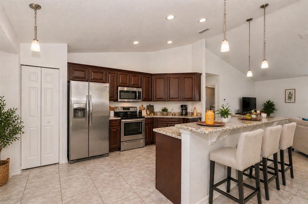 7153 Southeast 124th Street Belleview, FL 34420 - Photo 6 of 16 a kitchen with microwave a refrigerator and chairs