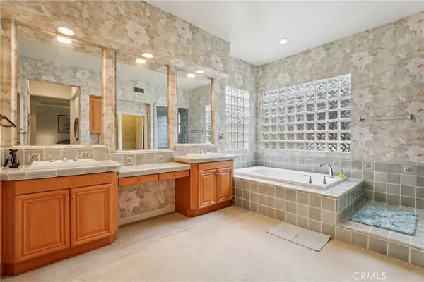 a bathroom with a granite countertop double vanity sink a bathtub a mirror and a bathtub