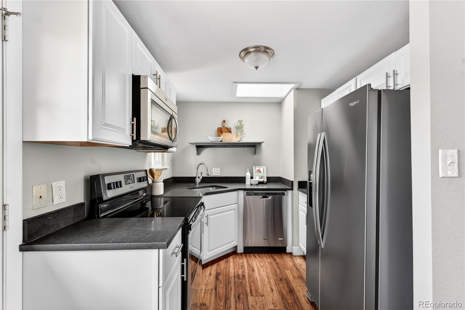 5246 Pierce Street Arvada, CO 80002 - Photo 8 of 30 a kitchen with stainless steel appliances granite countertop a refrigerator a stove and a sink with wooden floor