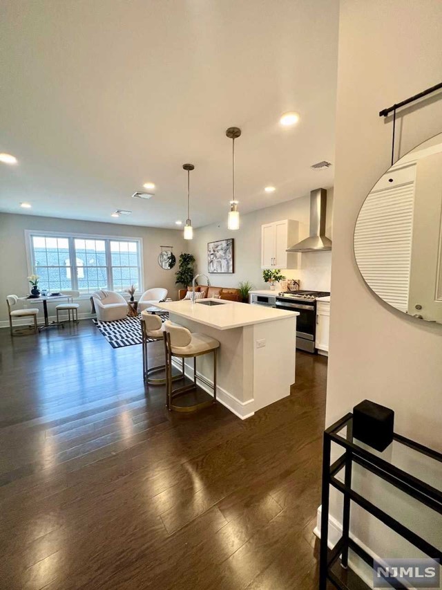 a living room with stainless steel appliances kitchen island granite countertop a table chairs and a living room