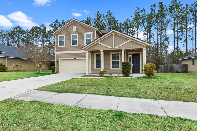 a front view of a house with a garden and trees