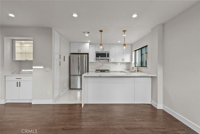 a kitchen with stainless steel appliances kitchen island granite countertop a refrigerator and a sink