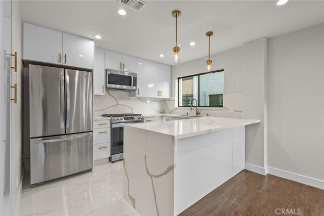 a kitchen with stainless steel appliances granite countertop a refrigerator a sink a stove and a refrigerator