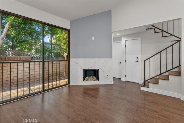 a view of a livingroom with wooden floor a fireplace and windows