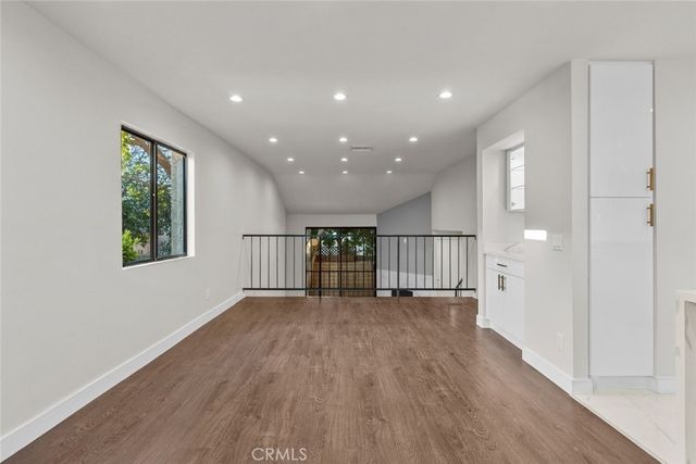 a view of empty room with wooden floor and windows