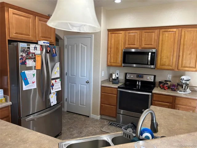 a kitchen with stainless steel appliances kitchen island granite countertop a refrigerator and a stove top oven