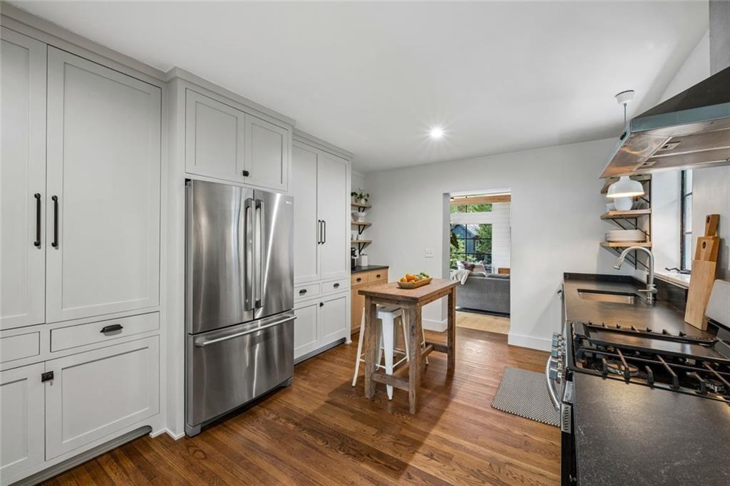 2069 Edinburgh Terrace Northeast Atlanta, GA 30307 - Photo 13 of 72 a kitchen with stainless steel appliances a refrigerator a stove a dining table and chairs with wooden floor