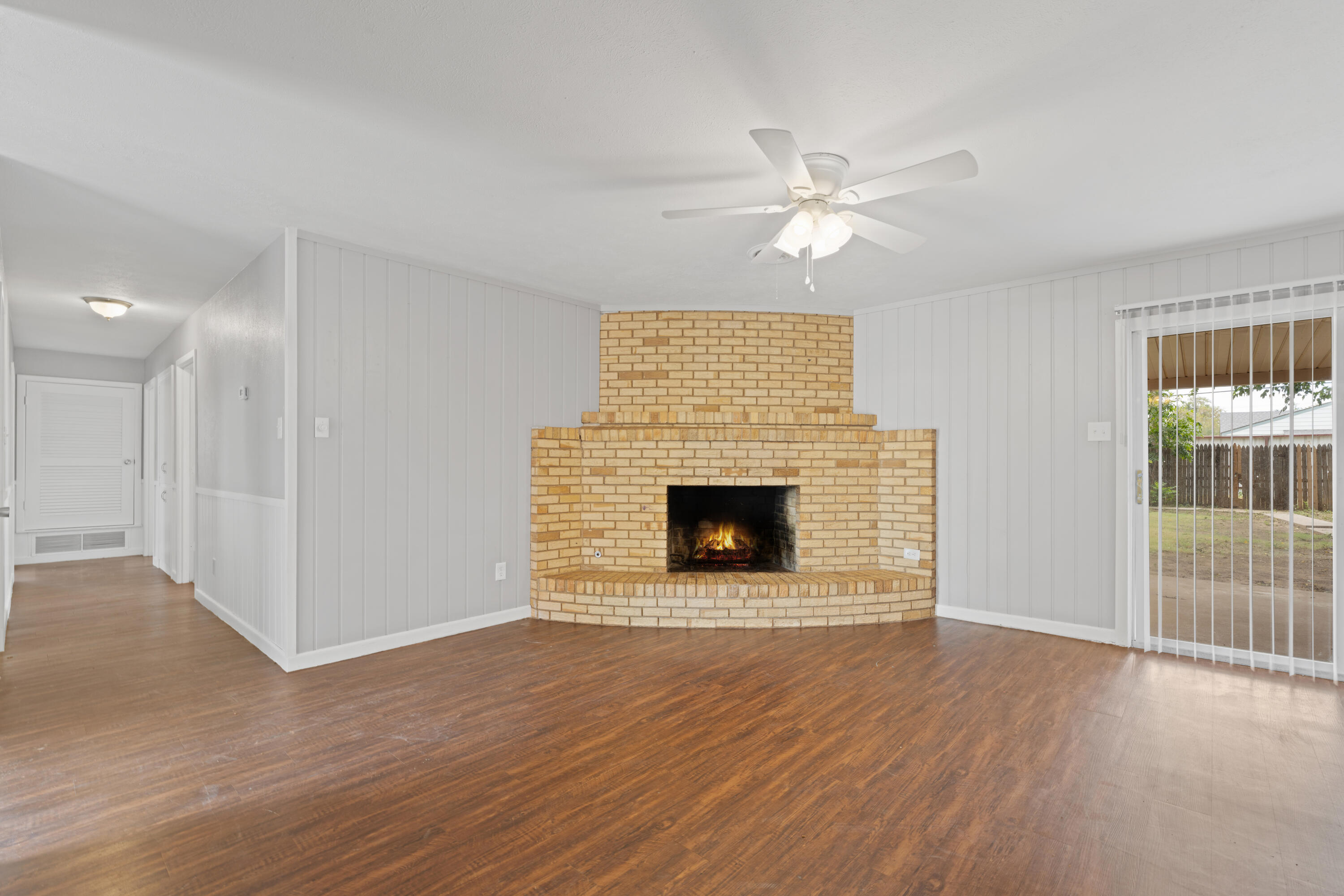 4609 31st Street Lubbock, TX 79410 - Photo 2 of 21 a view of a livingroom with a fireplace a ceiling fan and wooden floor