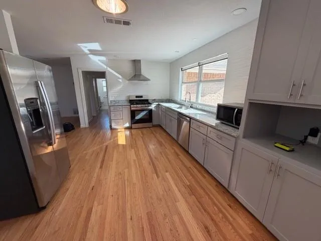 a kitchen with granite countertop wooden floors a sink and appliances