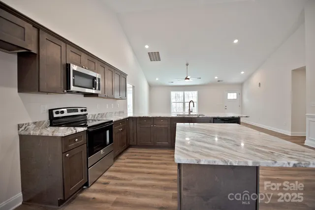 a large kitchen with stainless steel appliances granite countertop a stove a sink and a microwave