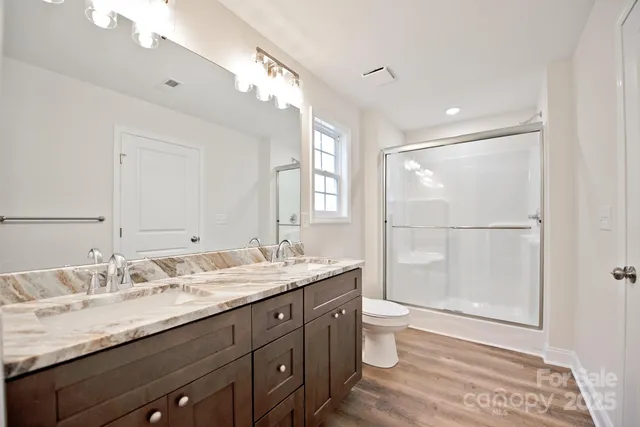 a bathroom with a granite countertop sink a toilet a mirror and shower