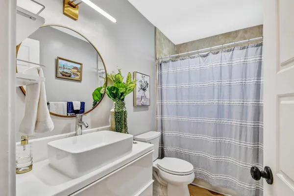 a bathroom with a sink a toilet a mirror and shower