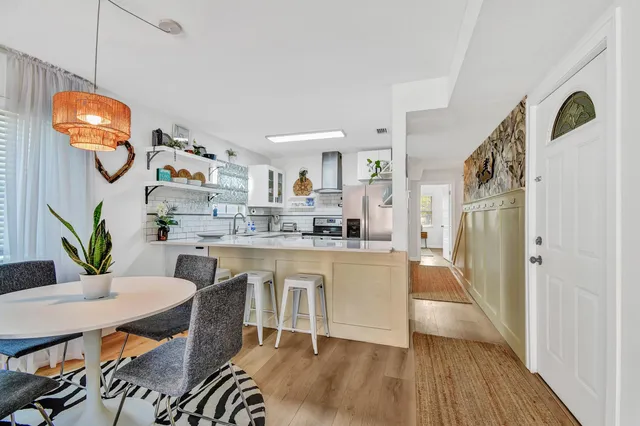 a kitchen with stainless steel appliances granite countertop a refrigerator a stove a microwave oven a dining table and chairs with wooden floor