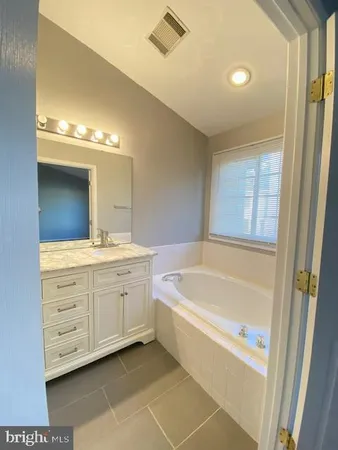 a spacious bathroom with a tub sink and mirror
