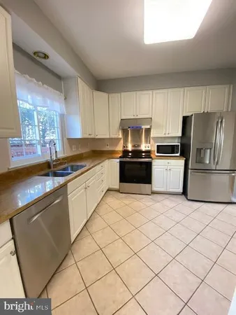 a kitchen with granite countertop a refrigerator stove top oven and sink