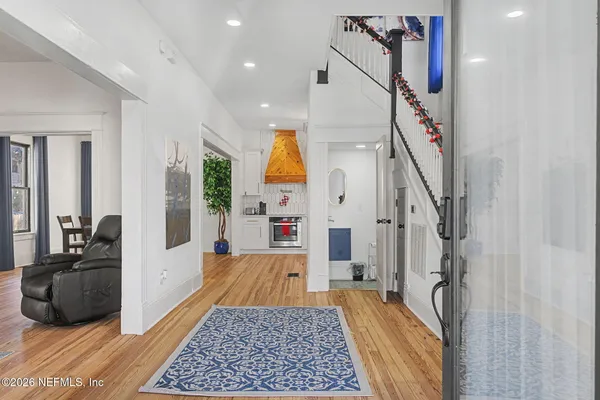 a kitchen with stainless steel appliances kitchen island granite countertop a refrigerator a stove a sink and white cabinets with wooden floor