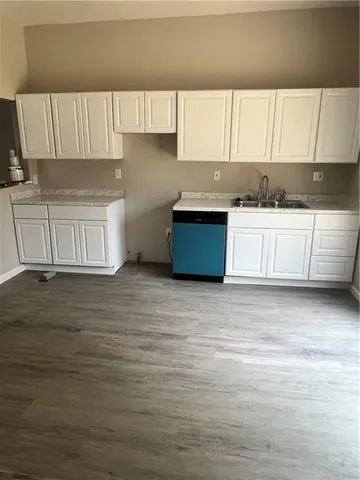 a kitchen with granite countertop a stove a sink and a white cabinets