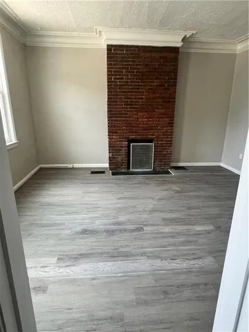 a view of an empty room with wooden floor and a fireplace