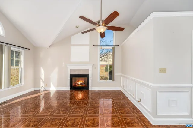 a view of a livingroom with a fireplace a ceiling fan and windows