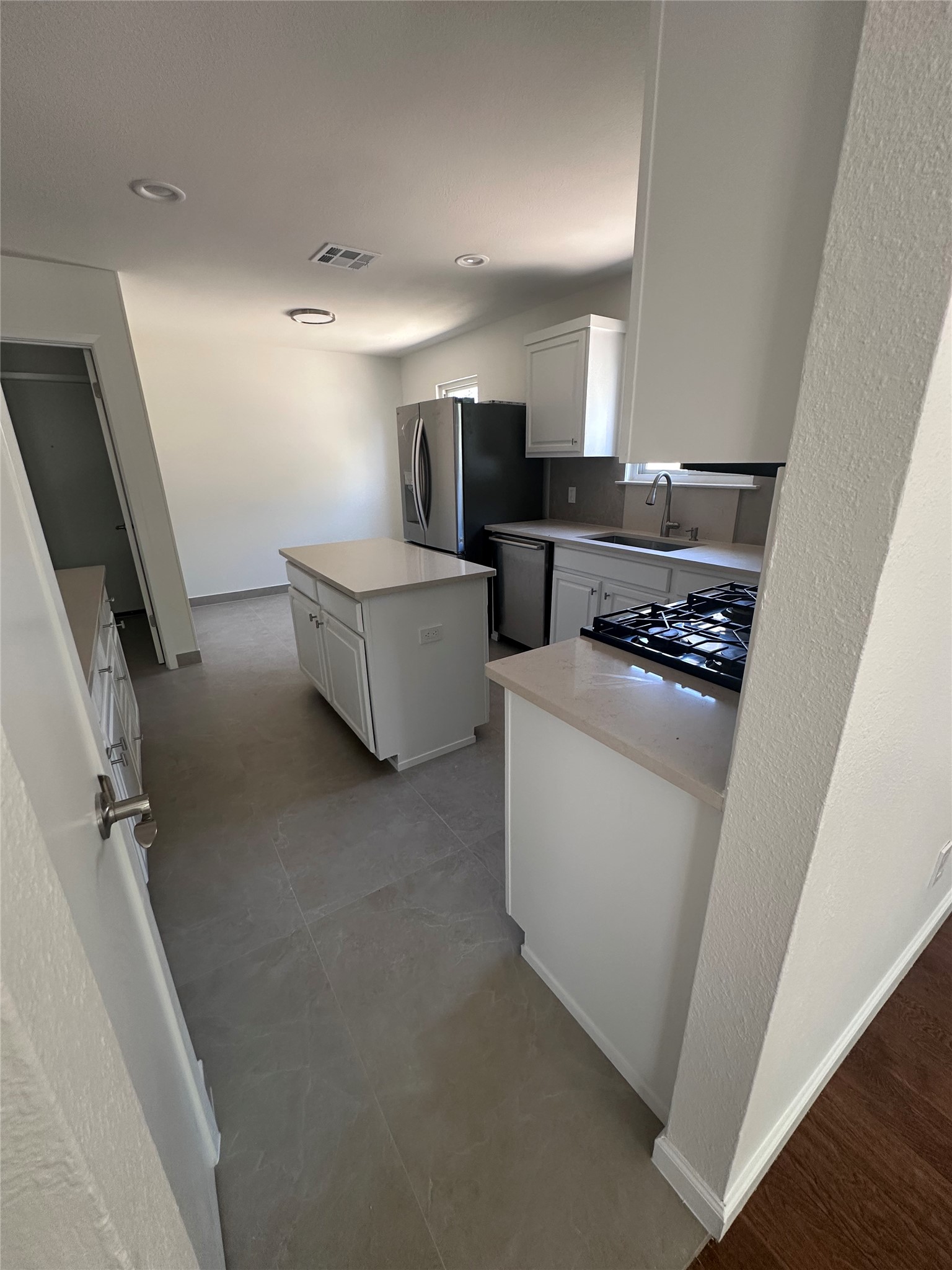 12610 Andromeda Cove Austin, TX 78727 - Photo 9 of 29 Smooth tile flooring, recessed lighting, and a functional central island anchor this updated kitchen space.