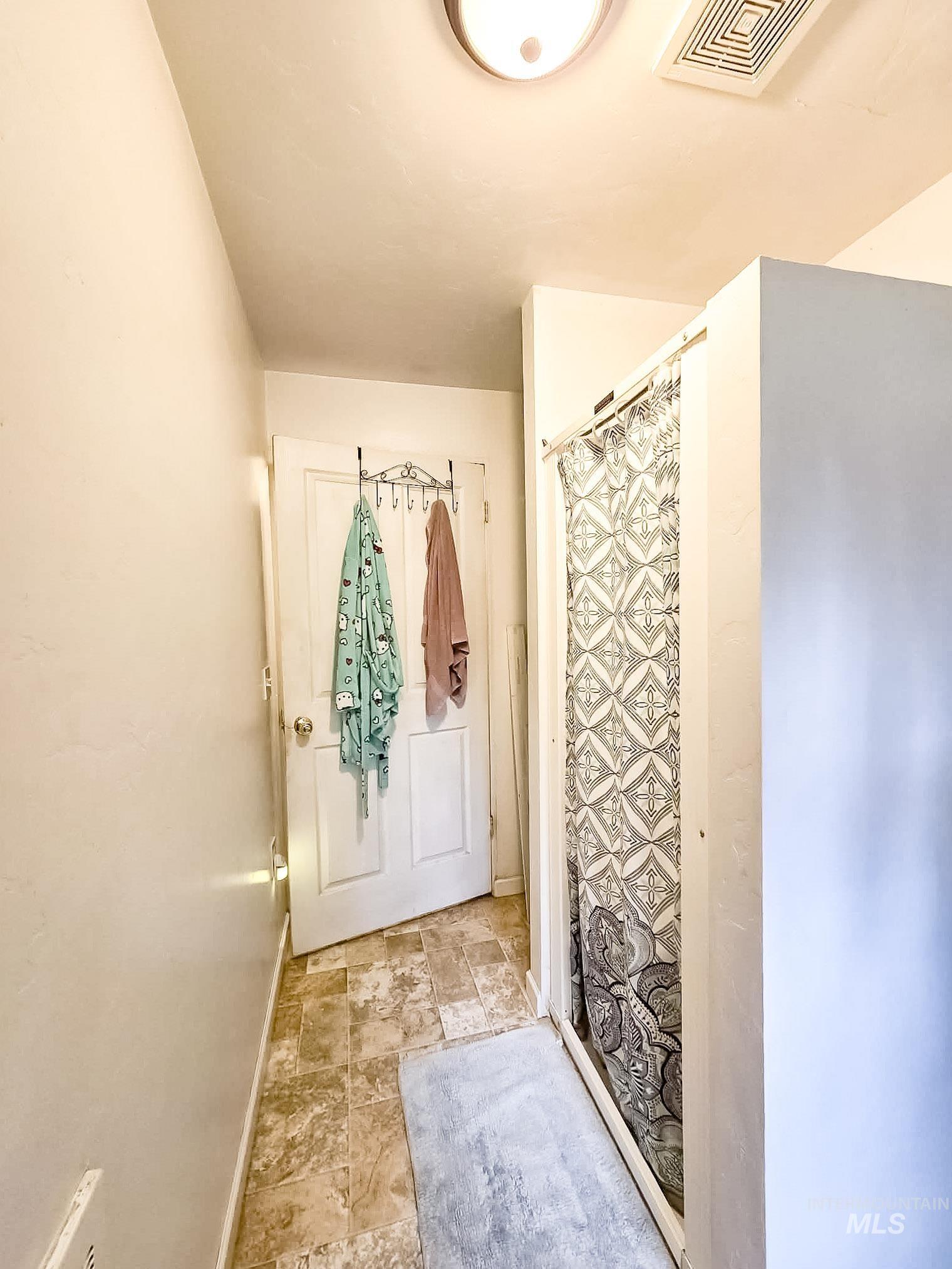 1650 Wells Bench Road Orofino, ID 83544 - Photo 24 of 44 Bathroom featuring a standing shower with a patterned curtain, textured flooring, and a ceiling-mounted light fixture