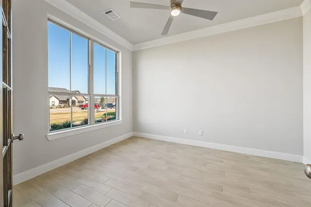 an empty room with windows and ceiling fan