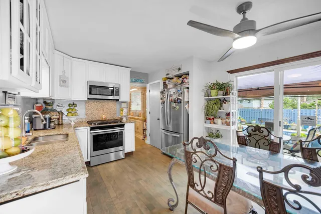 a kitchen with granite countertop a stove a sink a refrigerator and a dining table