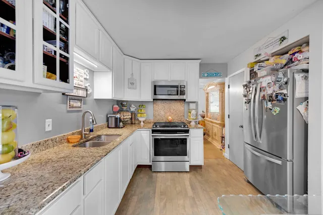 a kitchen with stainless steel appliances granite countertop a refrigerator a stove a sink and a microwave