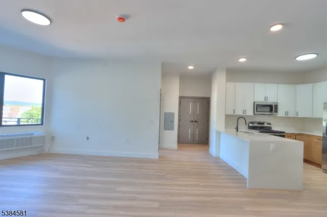 a view of kitchen with stainless steel appliances granite countertop a stove top oven a refrigerator a sink and dishwasher with wooden floor