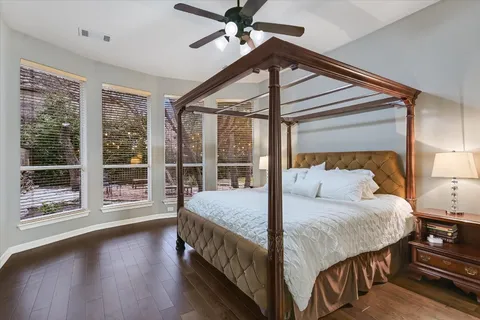 a bedroom with a bed and a large window with wooden floor