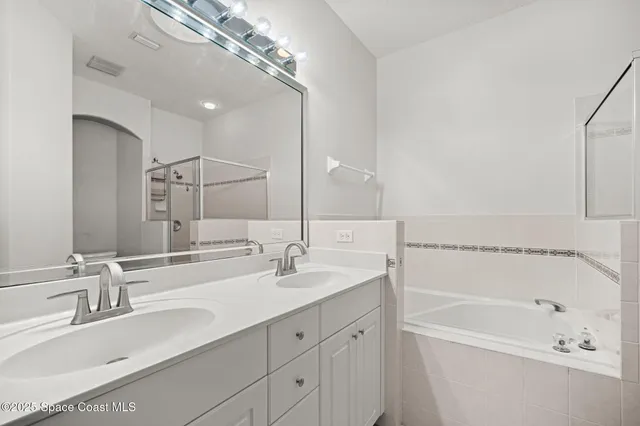 a bathroom with a tub a sink double vanity and mirror