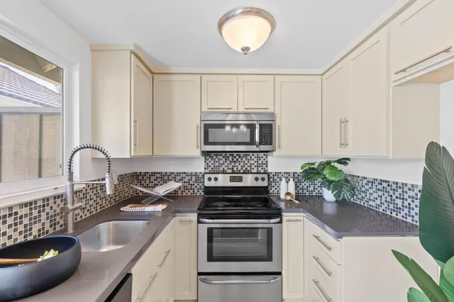 a kitchen with granite countertop a sink a stove and cabinets