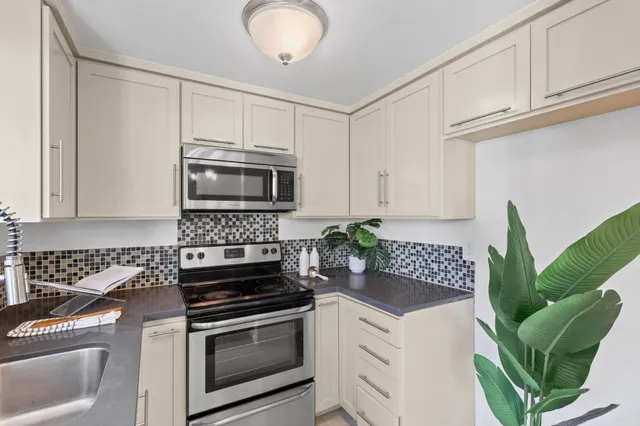 a kitchen with stainless steel appliances white cabinets and a stove top oven