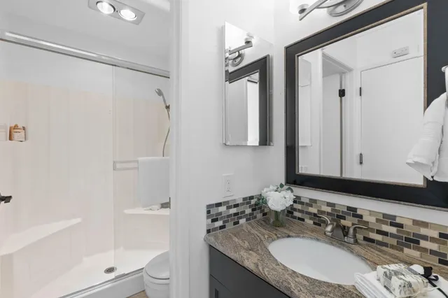 a bathroom with a granite countertop sink toilet and shower