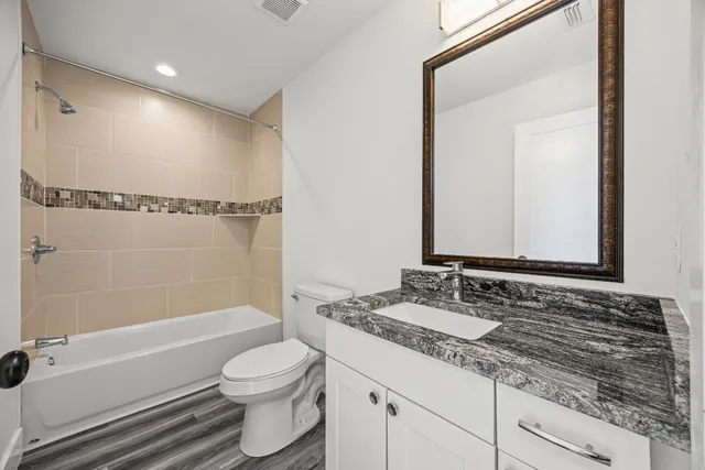a bathroom with a granite countertop sink toilet and shower