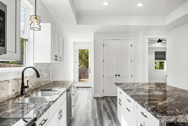 a kitchen with kitchen island granite countertop a sink stove and cabinets