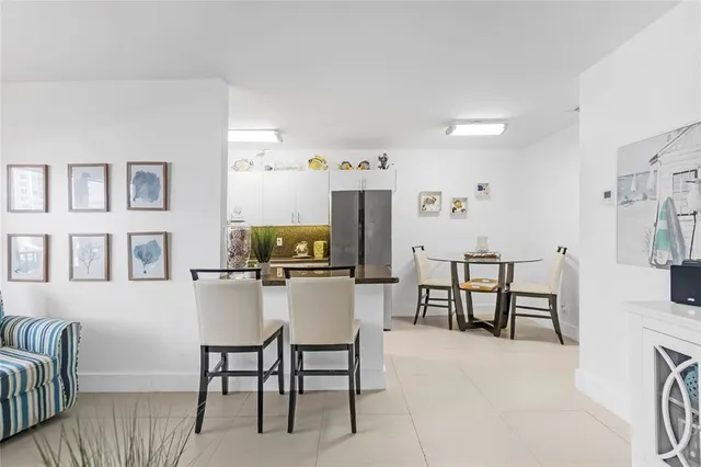 a kitchen with granite countertop a table chairs refrigerator and microwave