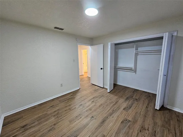 a view of an empty room with wooden floor and closet