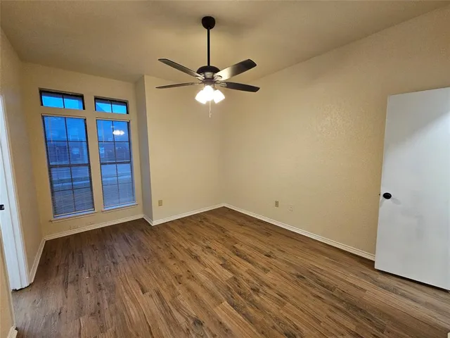 a view of room with hardwood floor and a ceiling fan