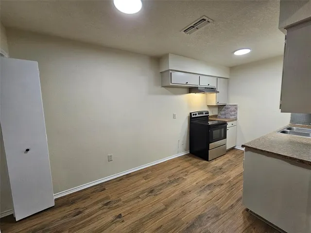a kitchen with granite countertop a sink cabinets and stainless steel appliances
