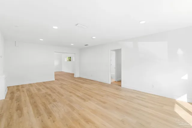 a view of an empty room with window and wooden floor