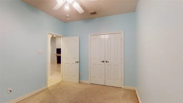an empty room with a hallway and chandelier fan