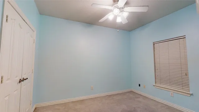 an empty room with a fan & a window