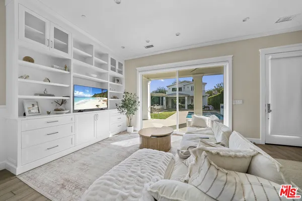 a living room with furniture cabinets and a large window