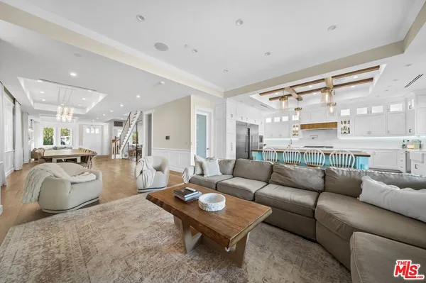 a living room with furniture a rug kitchen view and a large window