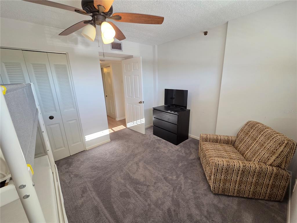 401 150th Avenue, Unit 223 Madeira Beach, FL 33708 - Photo 17 of 50 a living room with furniture a ceiling fan a lamp and a flat screen tv
